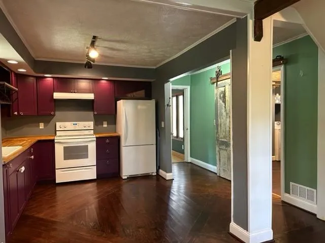 a kitchen with a refrigerator and wooden floor