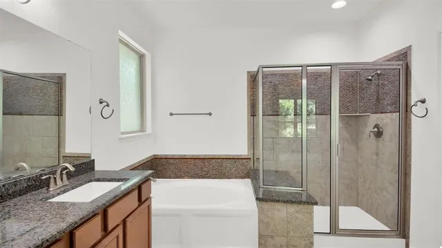a bathroom with a granite countertop sink a mirror and shower
