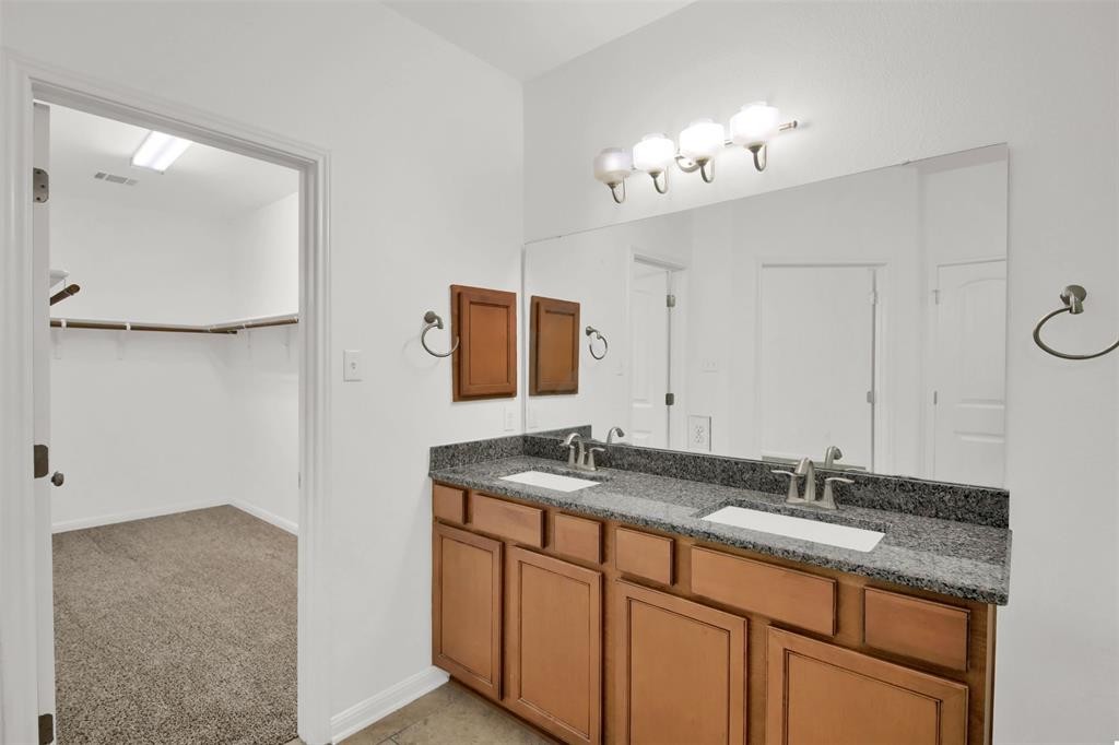 104 Lost Ridge Way Buda, TX 78610 - Photo 18 of 22 a bathroom with a granite countertop sink a mirror and a vanity