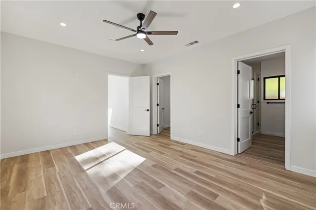 an empty room with wooden floor and a ceiling fan