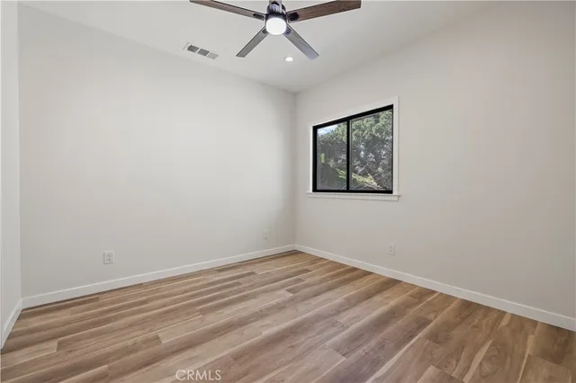 an empty room with a ceiling fan and window