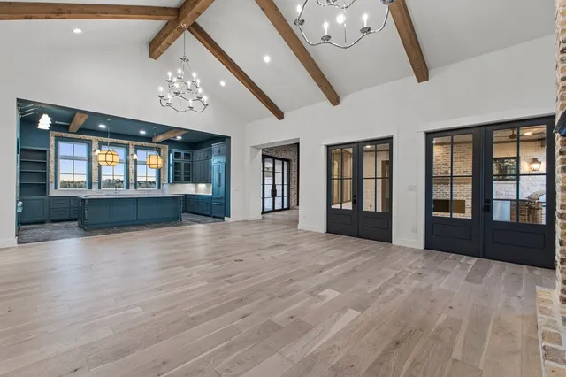 a view of an empty room with chandelier and wooden floor