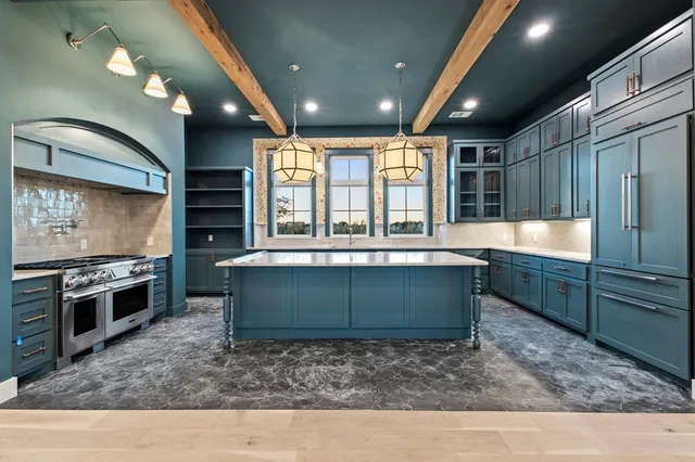 a kitchen with kitchen island granite countertop a stove and a sink with granite countertops