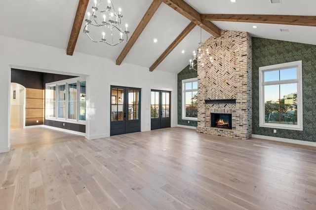 a view of an empty room with wooden floor and a fireplace