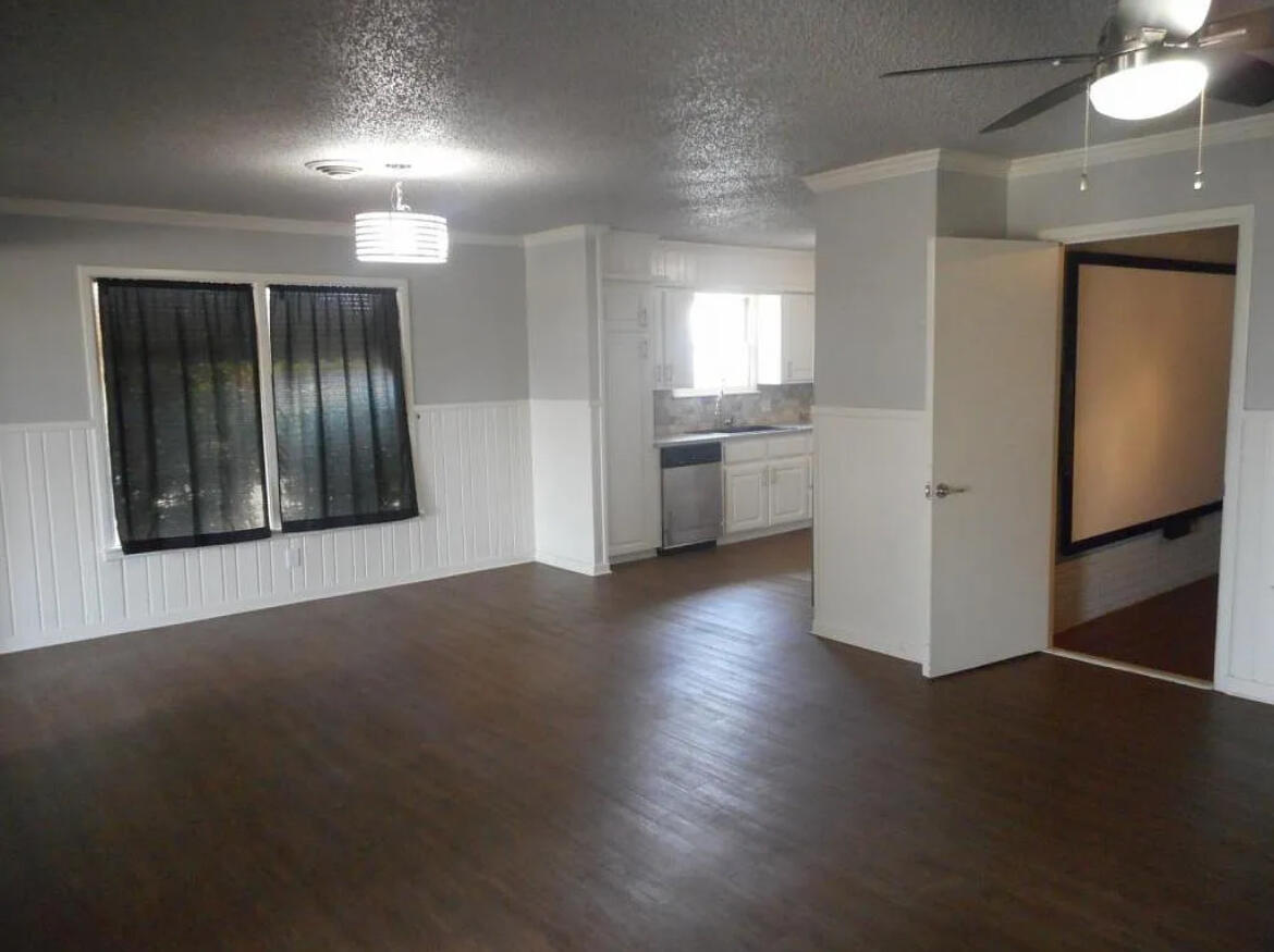 4901 12th Street Lubbock, TX 79416 - Photo 3 of 7 an empty room with wooden floor cabinet and windows