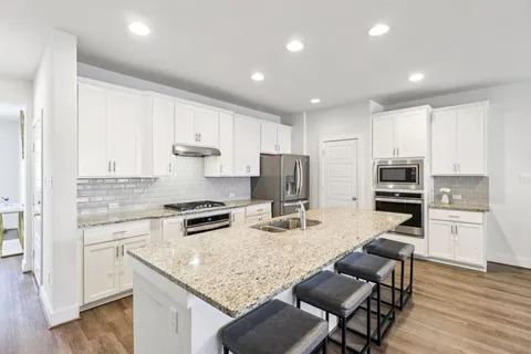 a kitchen with stainless steel appliances granite countertop a stove refrigerator and cabinets