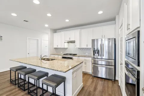 a kitchen with stainless steel appliances granite countertop a stove refrigerator sink and cabinets