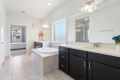 a spacious bathroom with a double vanity sink a mirror and a bathtub