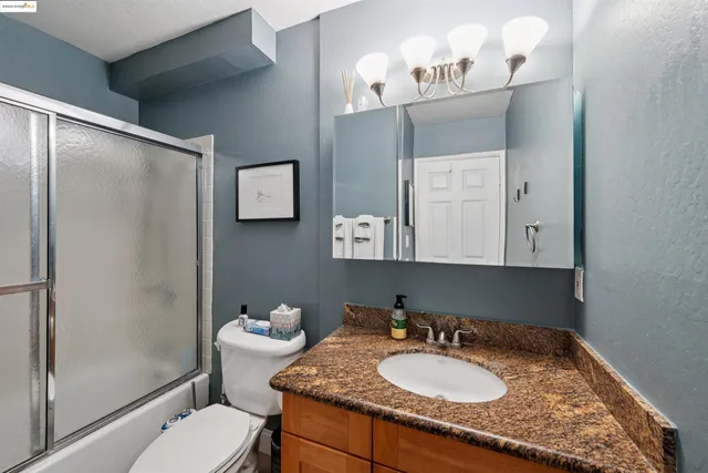a bathroom with a granite countertop sink toilet and shower