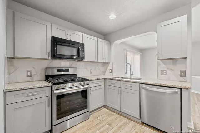a kitchen with cabinets stainless steel appliances a sink and wooden floor