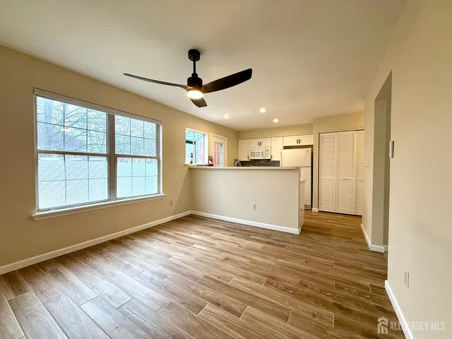 a view of an empty room with window and wooden floor