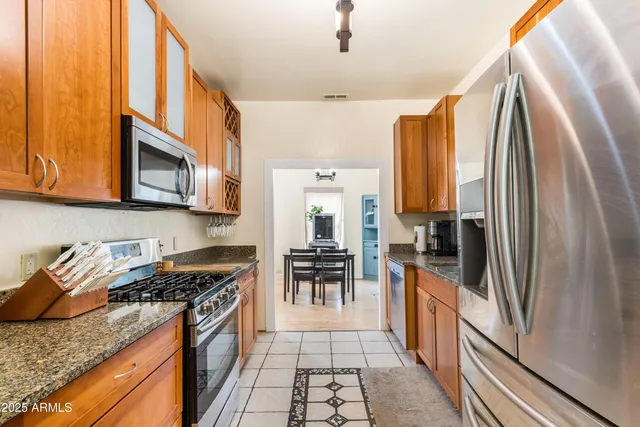 a kitchen with stainless steel appliances granite countertop a refrigerator and a stove top oven