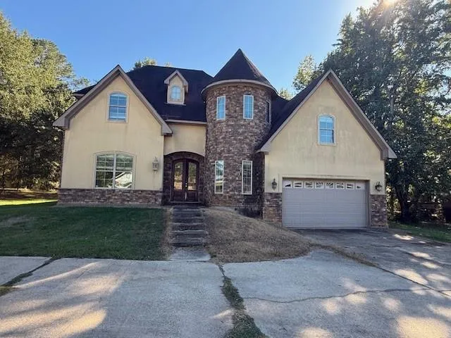 a view of a house with a yard and large tree
