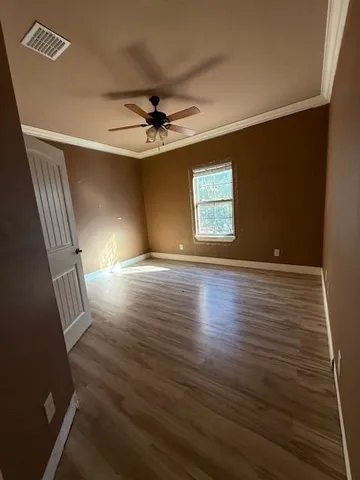a view of an empty room with a window and wooden floor