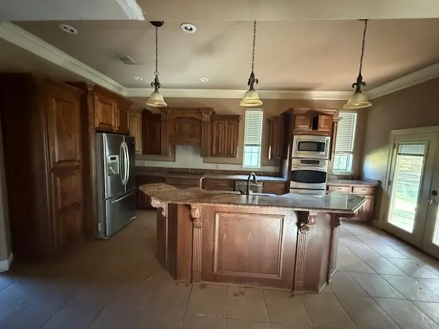 a kitchen with stainless steel appliances kitchen island granite countertop a refrigerator and a sink
