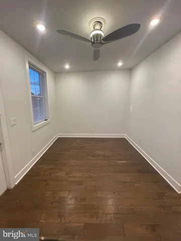 an empty room with wooden floor and chandelier fan
