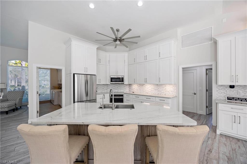 1850 Crayton Road Naples, FL 34102 - Photo 16 of 48 a kitchen with stainless steel appliances granite countertop a sink a stove a refrigerator a washer dryer and white cabinets