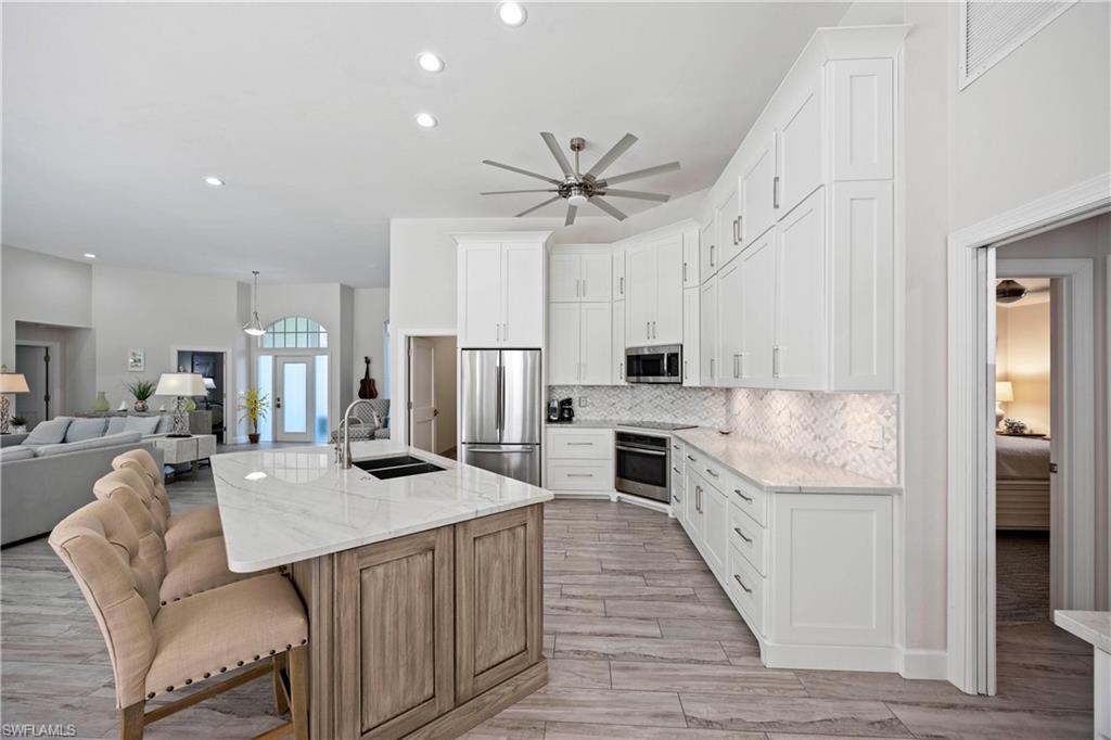 1850 Crayton Road Naples, FL 34102 - Photo 47 of 48 a kitchen with stainless steel appliances kitchen island granite countertop a refrigerator a stove a sink dishwasher and white cabinets with wooden floor