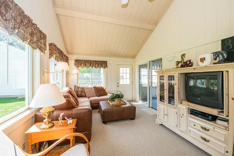 a living room with furniture a flat screen tv and a floor to ceiling window
