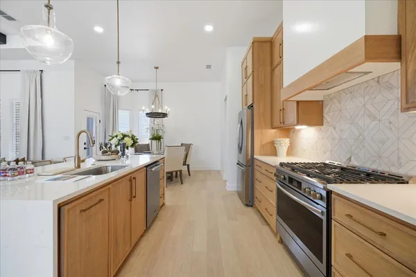 a kitchen with stainless steel appliances granite countertop a sink a stove and a wooden floors