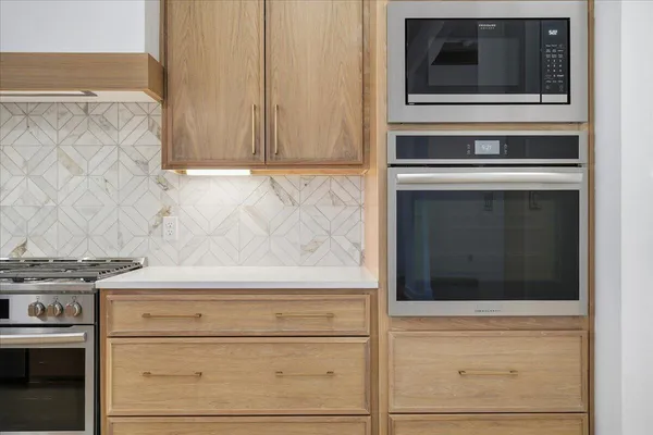 a dining hall with stainless steel appliances kitchen island granite countertop a table chairs and a refrigerator