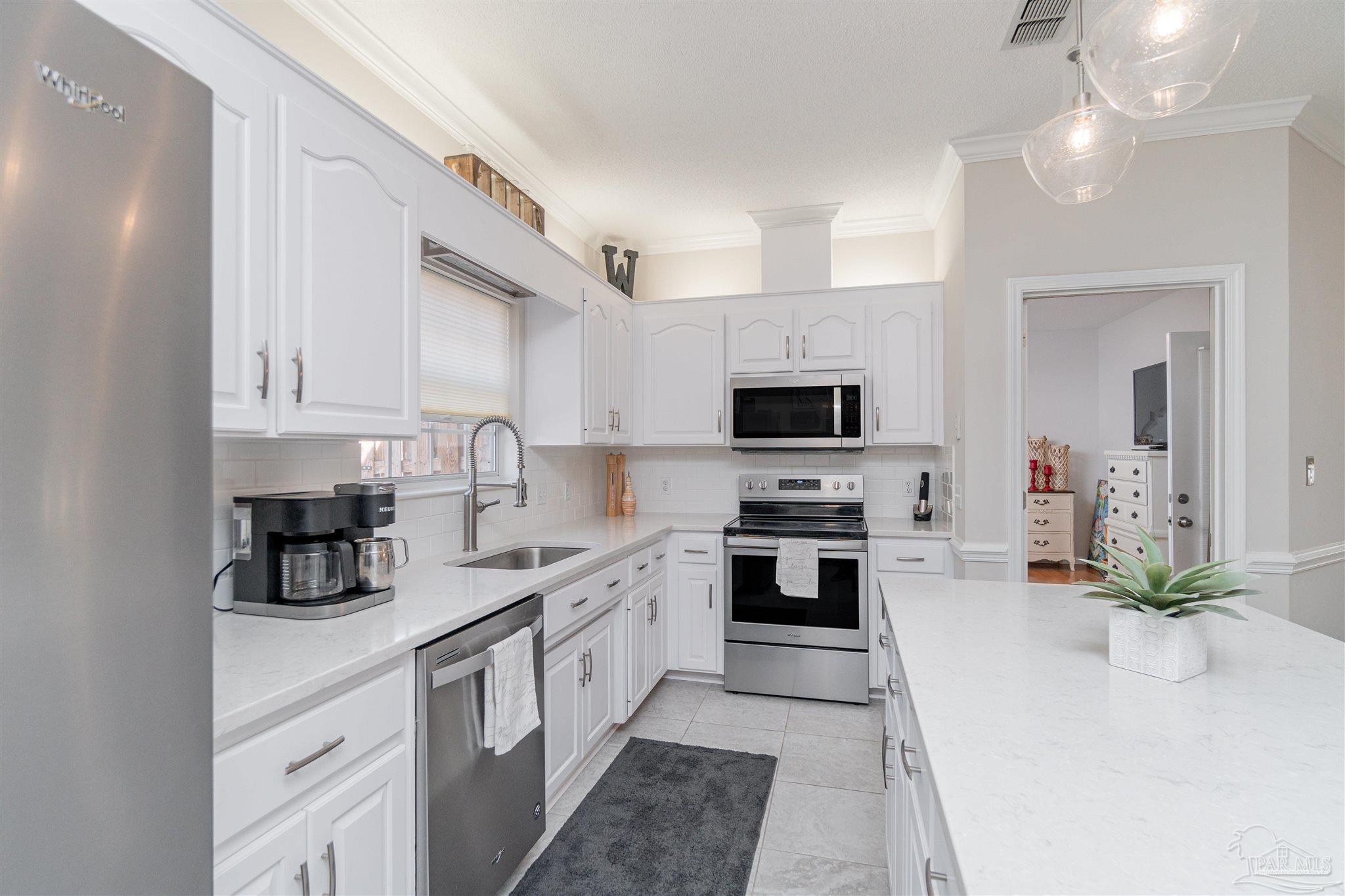 1504 Muirfield Road Cantonment, FL 32533 - Photo 10 of 17 a kitchen with stainless steel appliances a sink a stove top oven a counter space and cabinets
