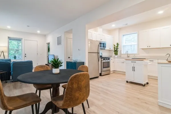 a kitchen with stainless steel appliances a dining table chairs and a refrigerator