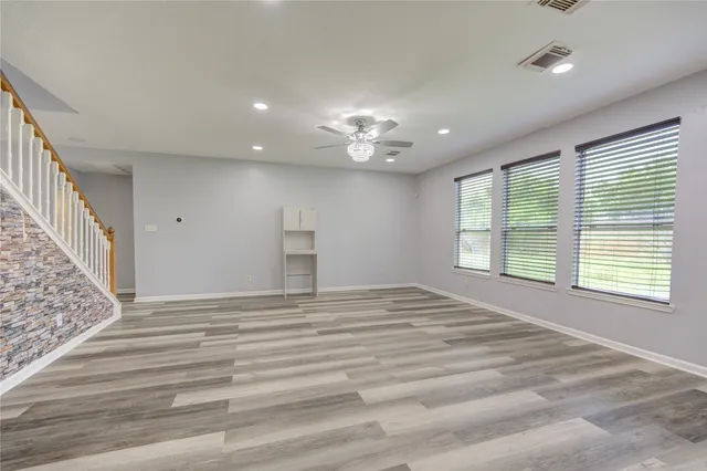 a view of an empty room with a window and a kitchen