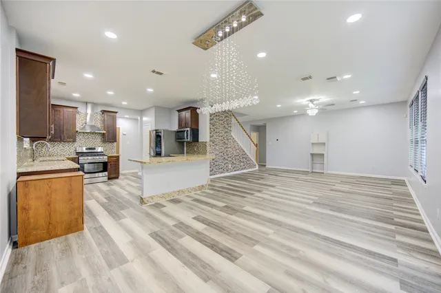 a large kitchen with granite countertop lots of counter space and stainless steel appliances