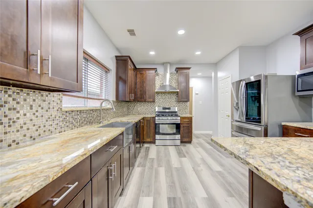 a kitchen with stainless steel appliances granite countertop a refrigerator and a stove top oven