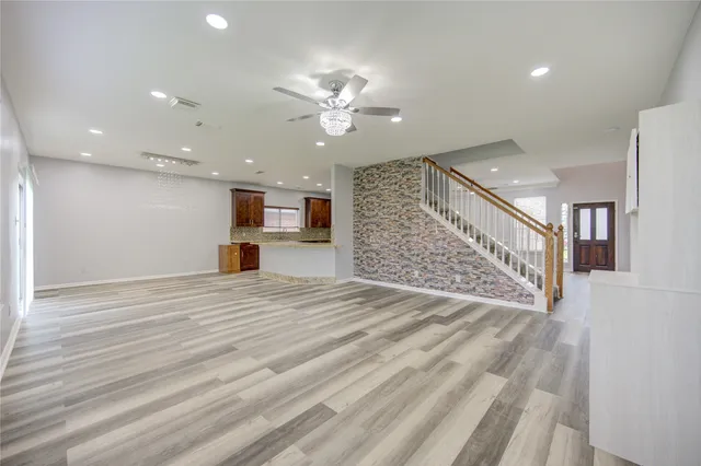 a view of an empty room with wooden floor and a ceiling fan