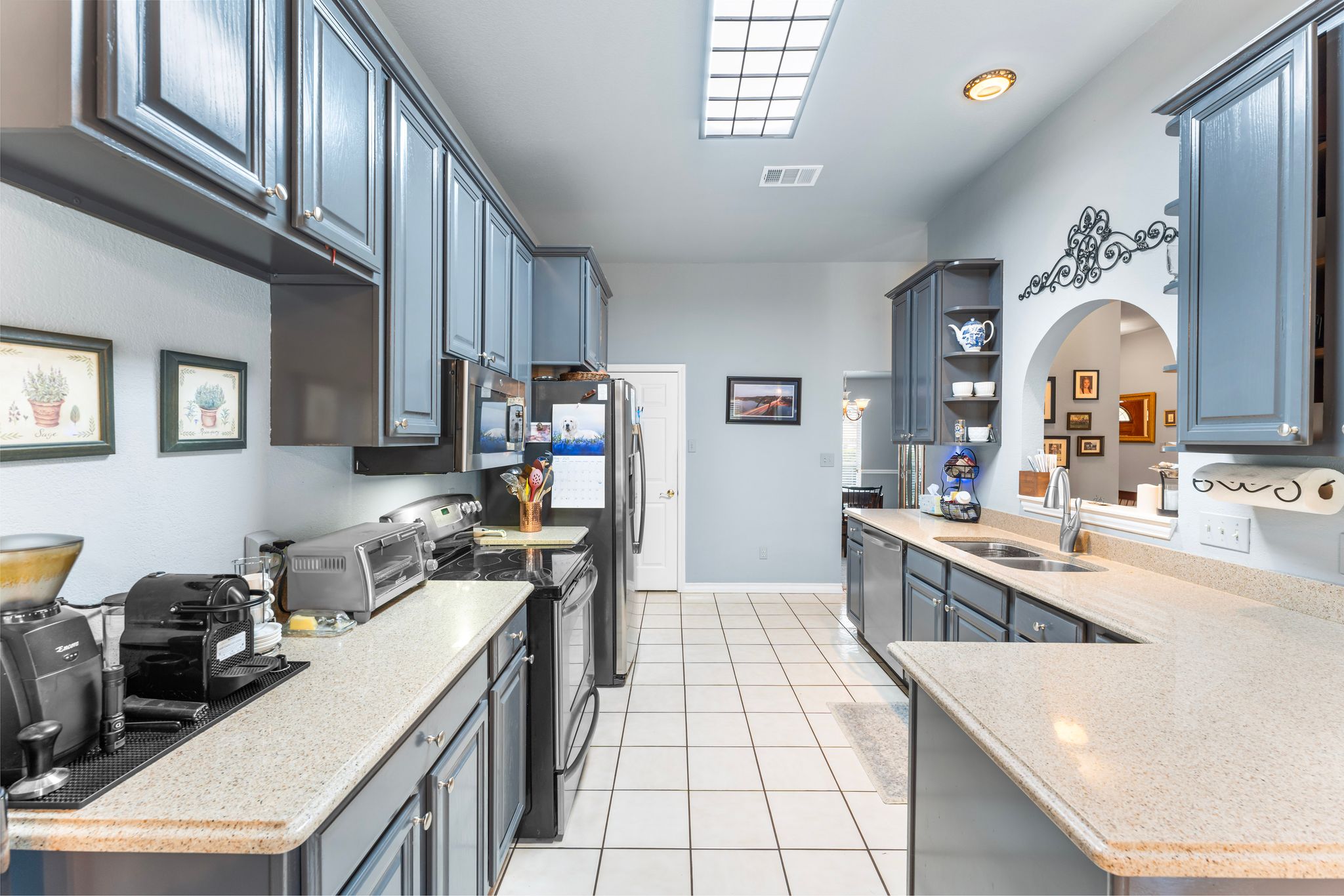 221 Breakaway Road Cedar Park, TX 78613 - Photo 24 of 39 Kitchen with appliances with stainless steel finishes, a sink, light tile patterned flooring, light countertops, and open shelves