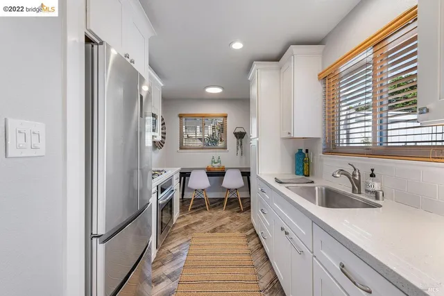 a large white kitchen with stainless steel appliances granite countertop a sink and a window
