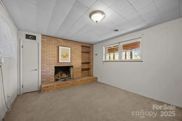 a view of an empty room with a fireplace and a window