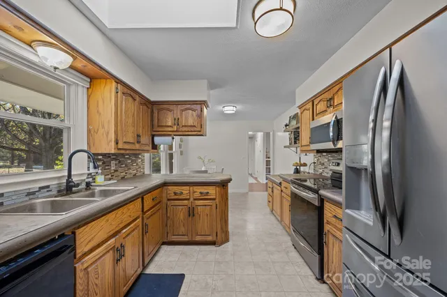 a large kitchen with stainless steel appliances granite countertop a sink stove and refrigerator