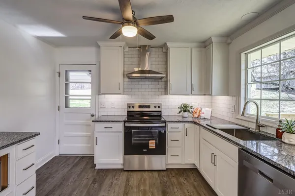 an empty room with wooden floor ceiling fan and windows