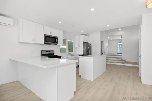 a kitchen with stainless steel appliances a stove a microwave a sink a refrigerator and white cabinets