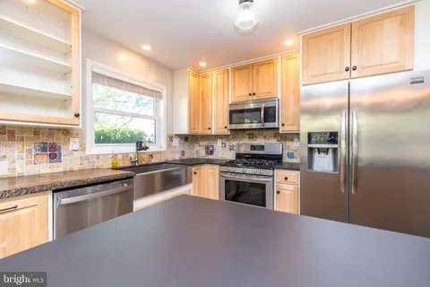 a kitchen with kitchen island granite countertop a stove refrigerator and a sink