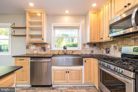a kitchen with stainless steel appliances granite countertop a stove a sink and a microwave