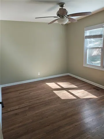 a view of a room with wooden floor a ceiling fan and windows