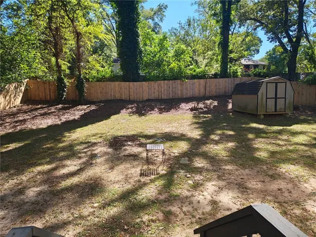a view of a backyard with large trees and wooden fence