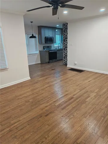 an empty room with kitchen and a wooden floor