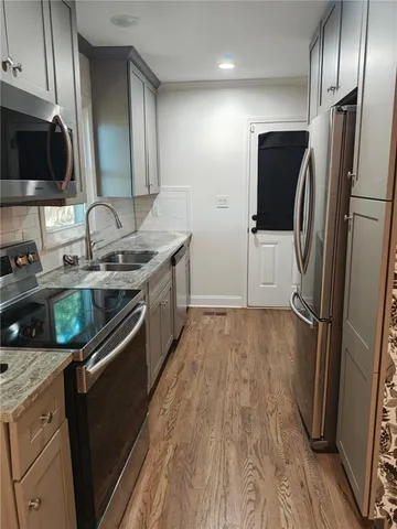 a kitchen with stainless steel appliances granite countertop a refrigerator a sink a stove and a wooden floors