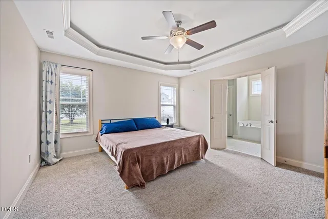 a spacious bedroom with a bed painting on wall and windows