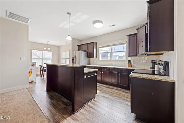 a kitchen with stainless steel appliances granite countertop a stove a sink dishwasher a refrigerator and a oven with wooden floor