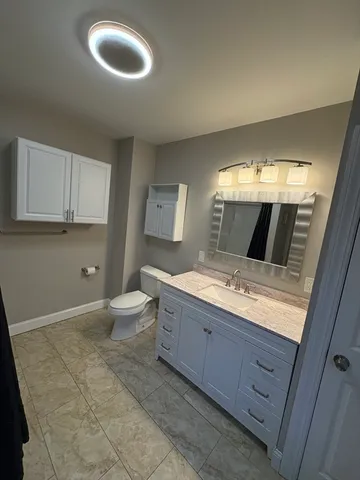 a bathroom with a granite countertop sink a toilet and a mirror