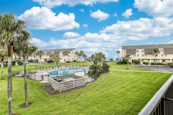 a view of pool with lawn chairs and a big yard