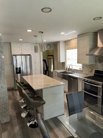 a kitchen with stainless steel appliances kitchen island a table chairs in it and wooden floors