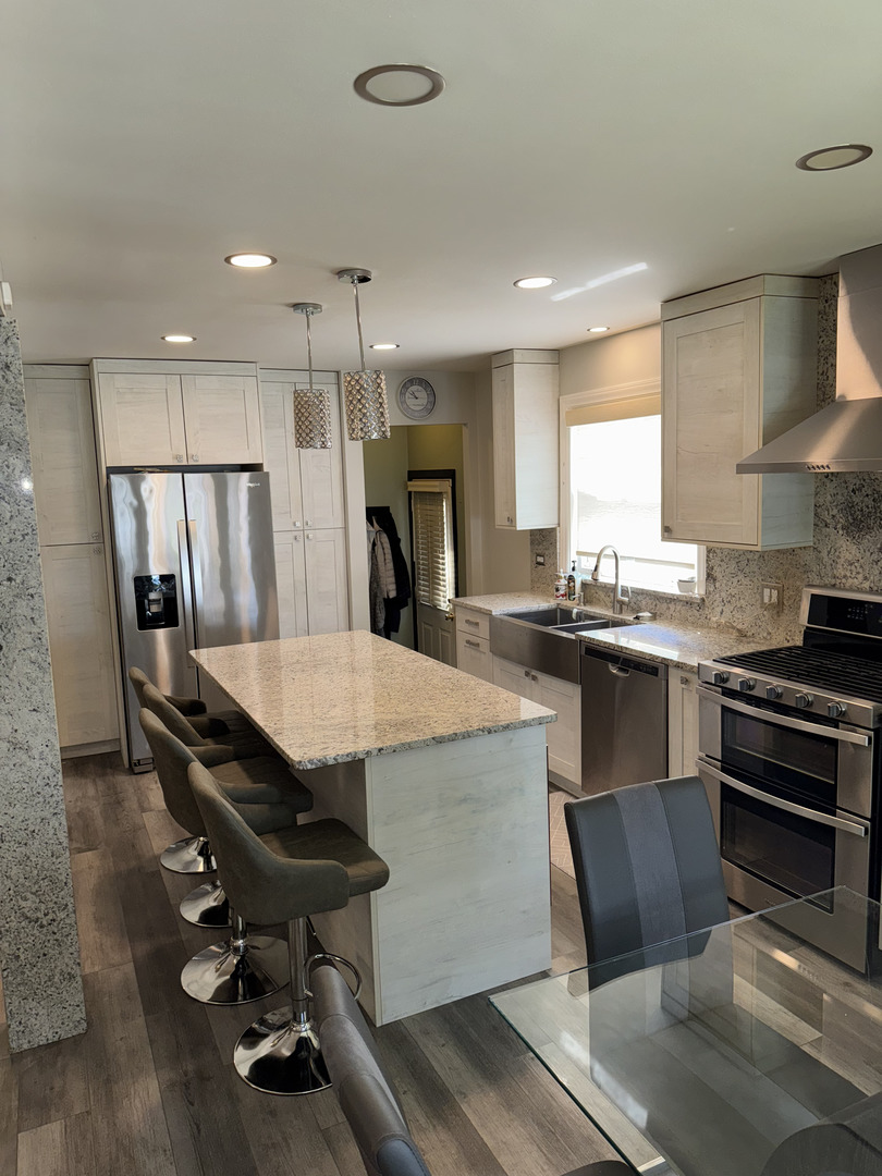 2527 Keystone Avenue North Riverside, IL 60546 - Photo 7 of 33 a kitchen with stainless steel appliances kitchen island a table chairs in it and wooden floors