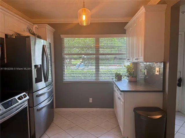 a kitchen with granite countertop a refrigerator a sink and white cabinets
